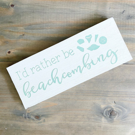 Wooden sign with 'I'd rather be beachcombing' text on a wooden surface