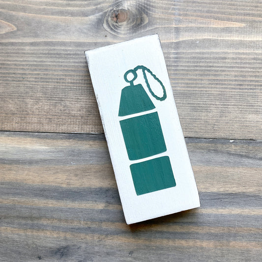 White sign with dark green buoy design on a wooden surface