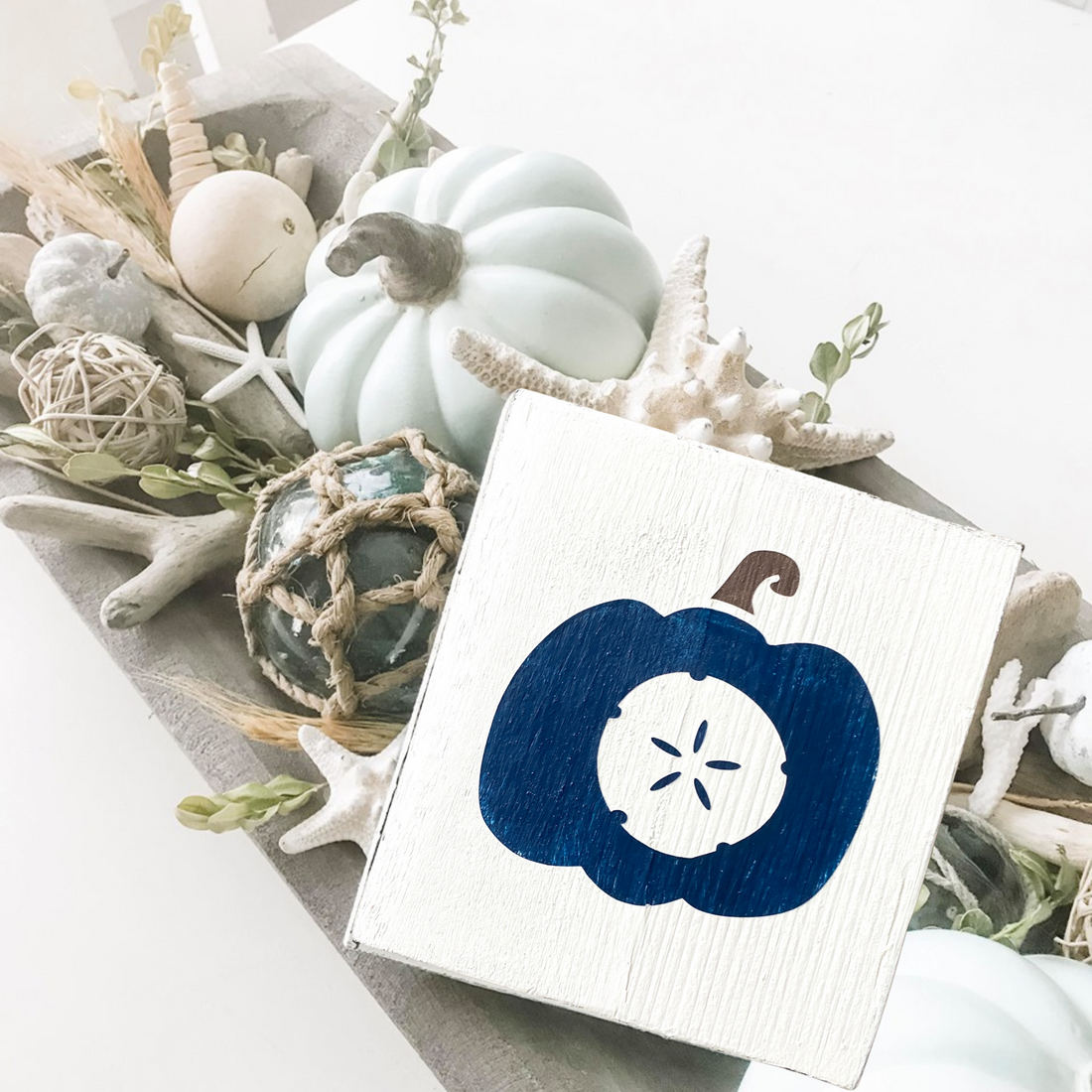 Easy coastal fall dough bowl centerpiece with blue and white pumpkins, driftwood, sea glass floats, and a handmade coastal fall sign from Anchored Soul Designs