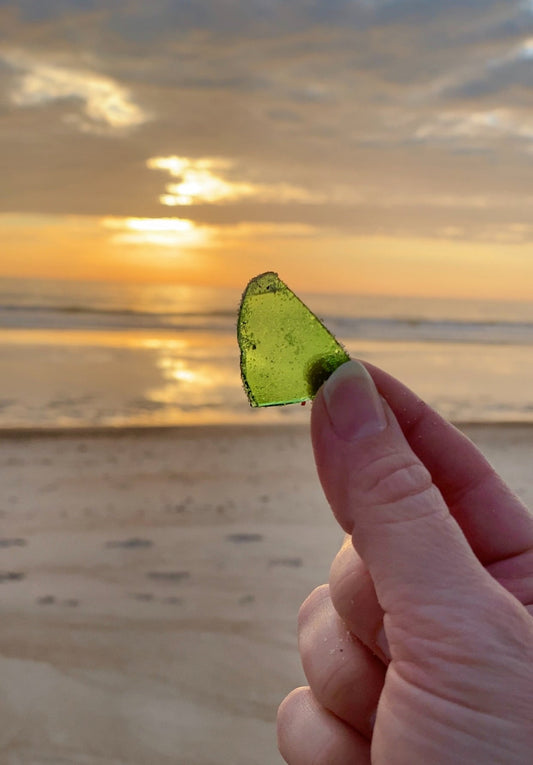 green sea glass pieces found on the beach at sunrise