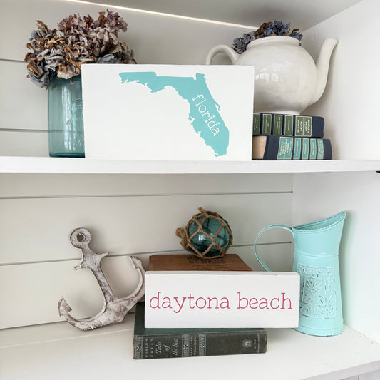 which companies offer custom beach inspired wall art prints, custom location signs for coastal home decor, florida sign and daytona beach sign on a shelf with beach decor