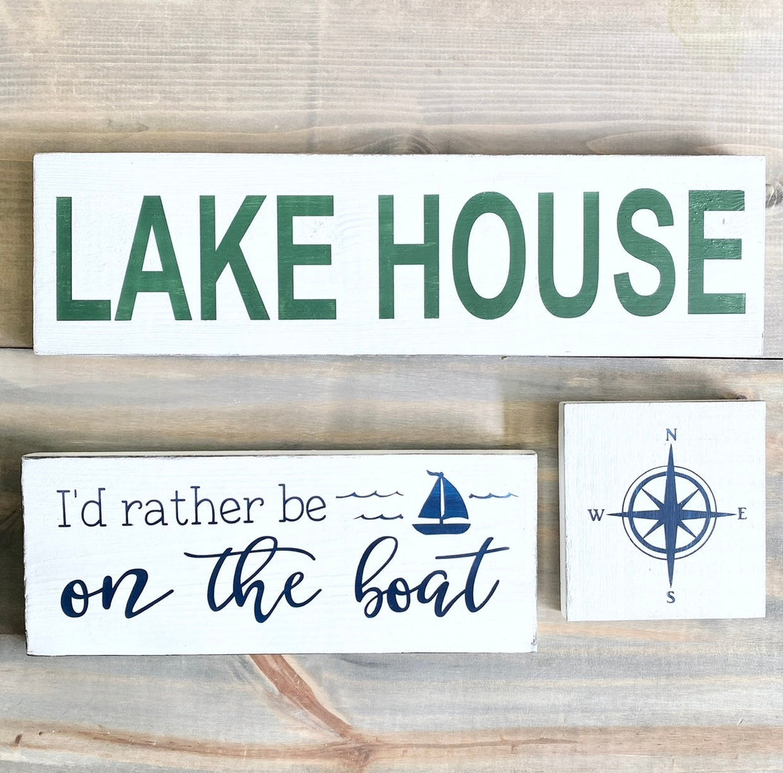 Handmade lake house signs including I'd Rather Be on the Boat and Compass Sign displayed as gifts for lake house lovers, hand-painted to order on Amelia Island Florida in your choice of colors