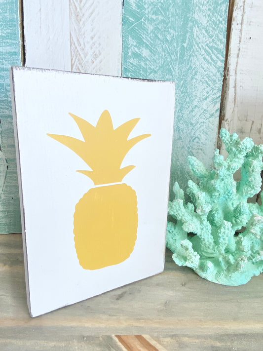 pineapple sign in white and yellow, with aqua coral and wood backdrop, coastal home decor for the best coastal colors yellow