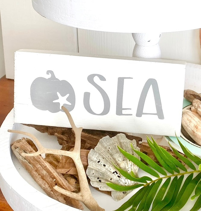 Handmade Sea Pumpkin Sign displayed in a tiered tray with shells and driftwood, coastal fall decor for beach houses and seaside homes hand-painted to order on Amelia Island Florida