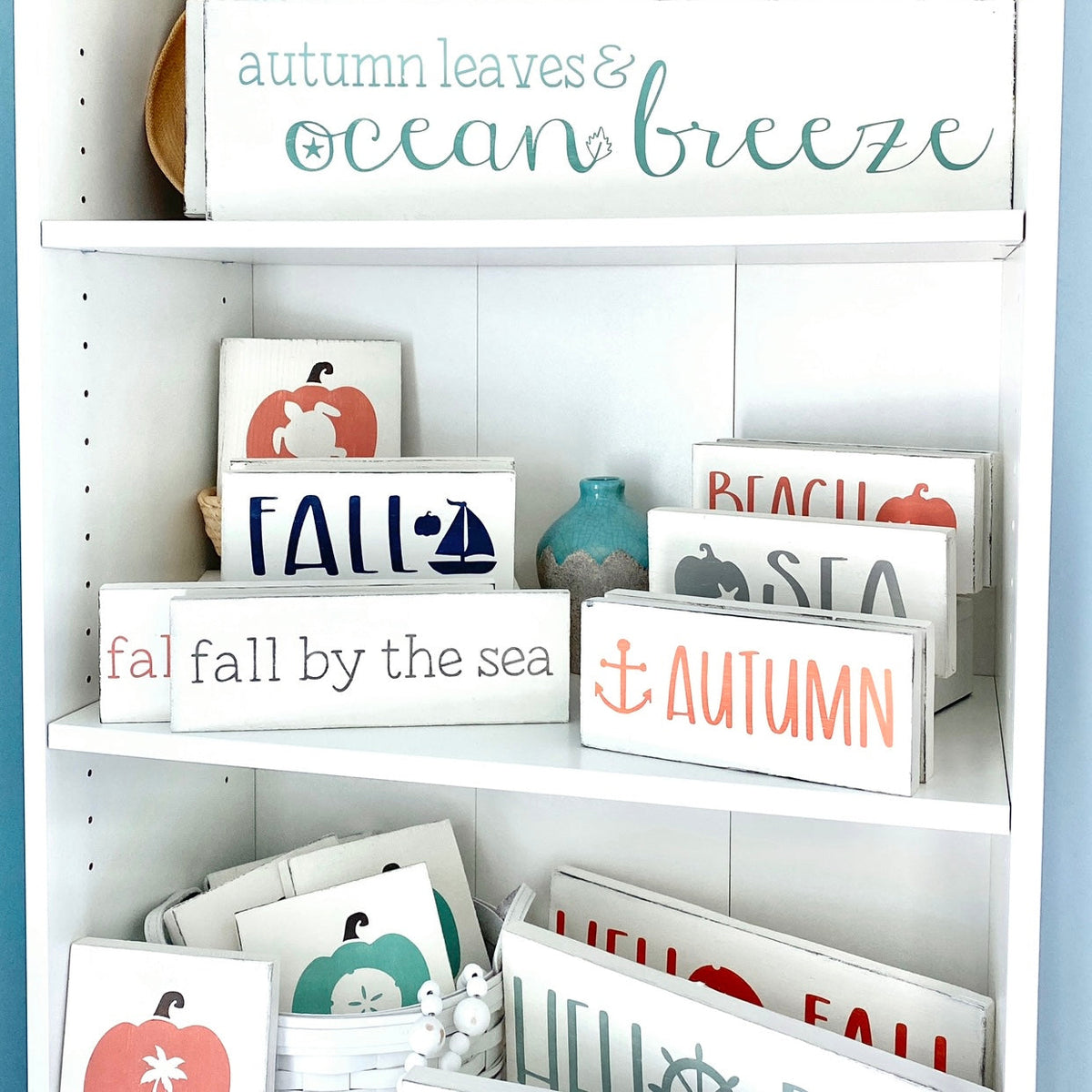 Handmade nautical fall signs displayed on a shelf including anchor, ship wheel, and coastal pumpkin designs, hand-painted to order on Amelia Island Florida for beach house and coastal home fall decor