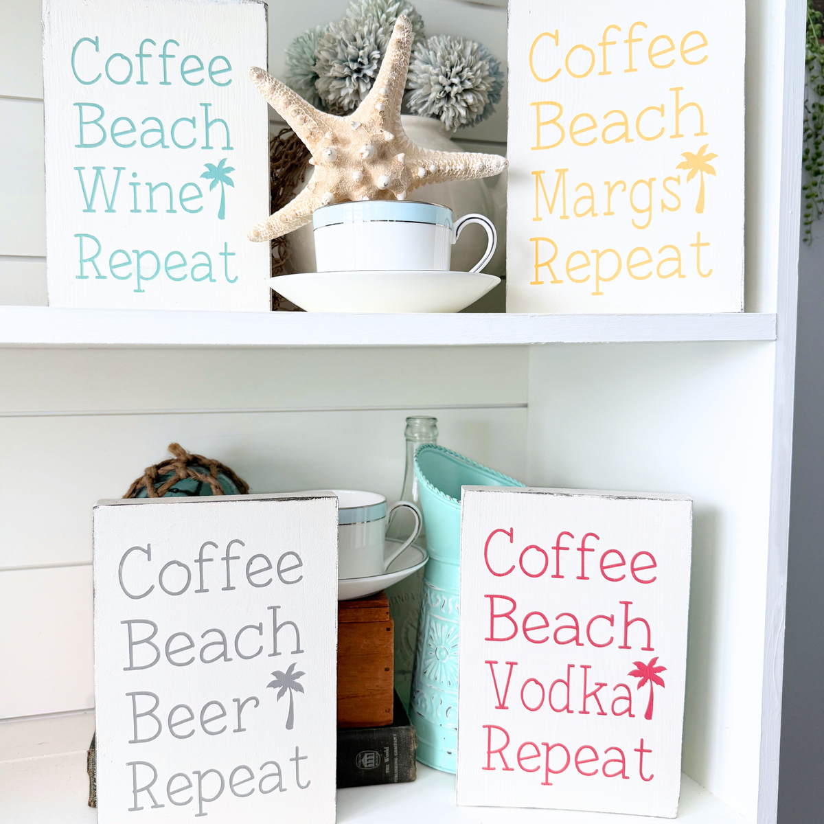 Decorative signs with humorous phrases on a shelf with decorative items. Coffee beach "drink" repeat signs coastal home decor signs