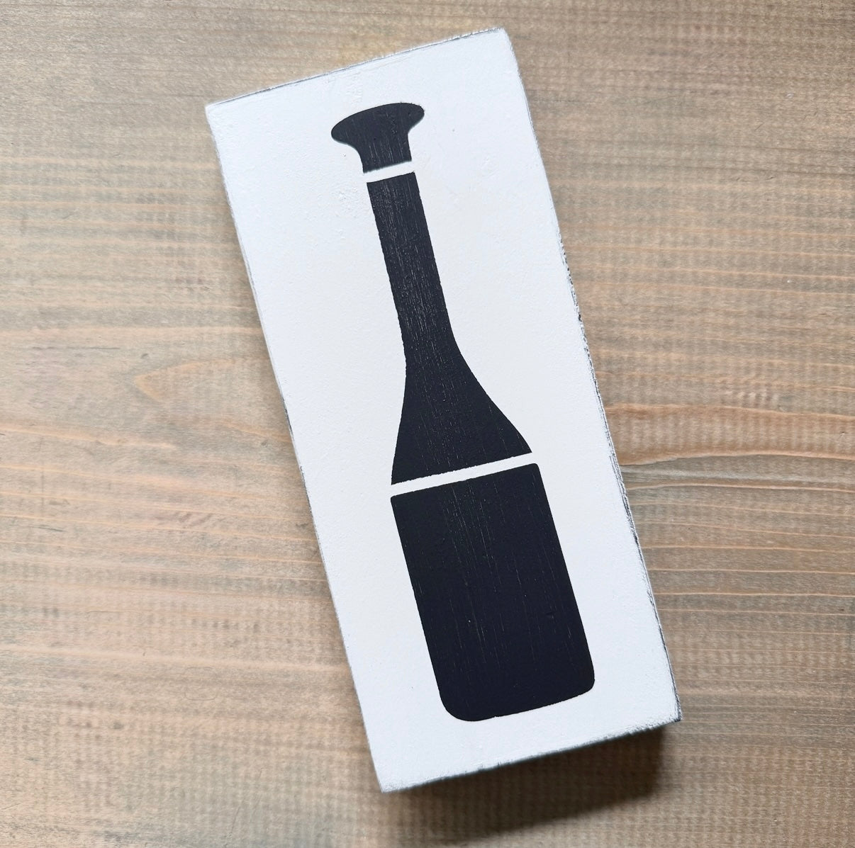 White sign with black oar design on a wooden surface coastal decor