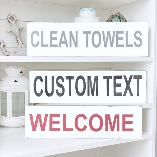 Decorative sign with 'Clean Towels' 'Custom Text' and 'Welcome' on a shelf.