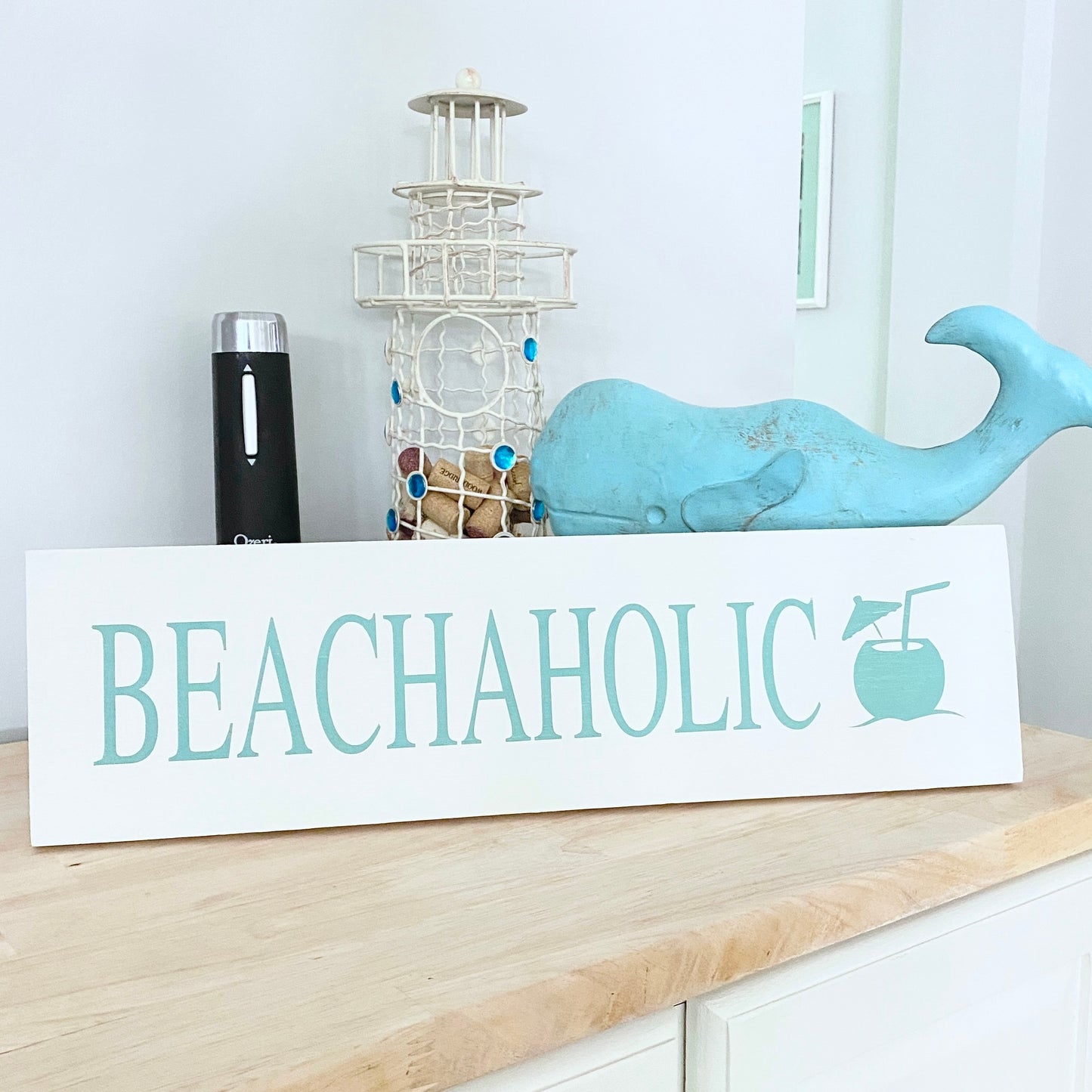 Decorative sign with 'BEACHAHOLIC' text on a shelf with decorative items.