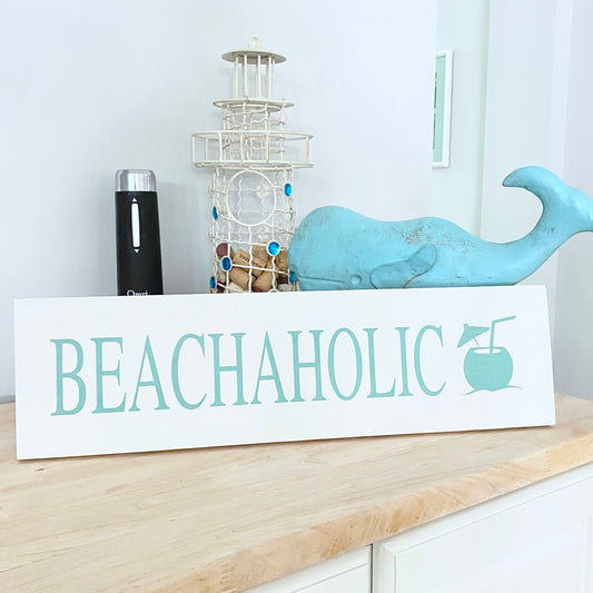 Decorative sign with 'BEACHAHOLIC' text on a shelf with decorative items.