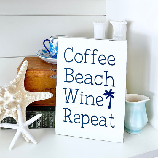 Decorative sign with 'Coffee Beach Wine Repeat' text on a shelf with starfish and mugs.