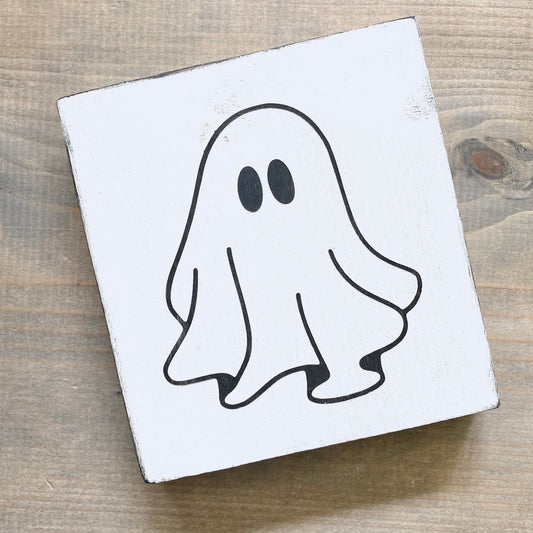 Ghost image on a white square sign with black outline on a wooden surface