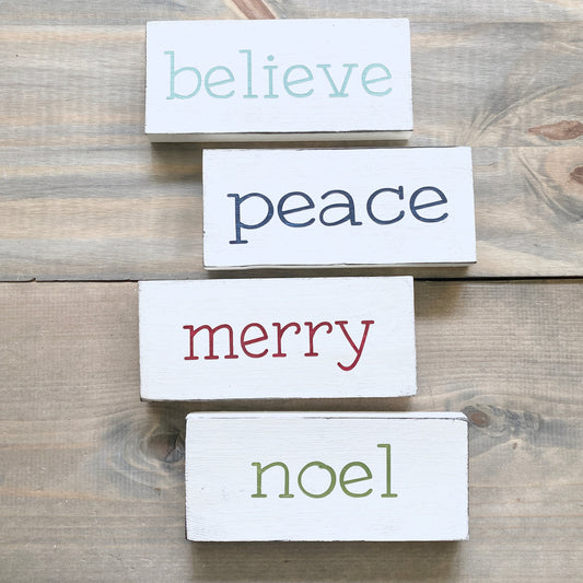 Set of wooden signs with Christmas-themed words on a wooden surface