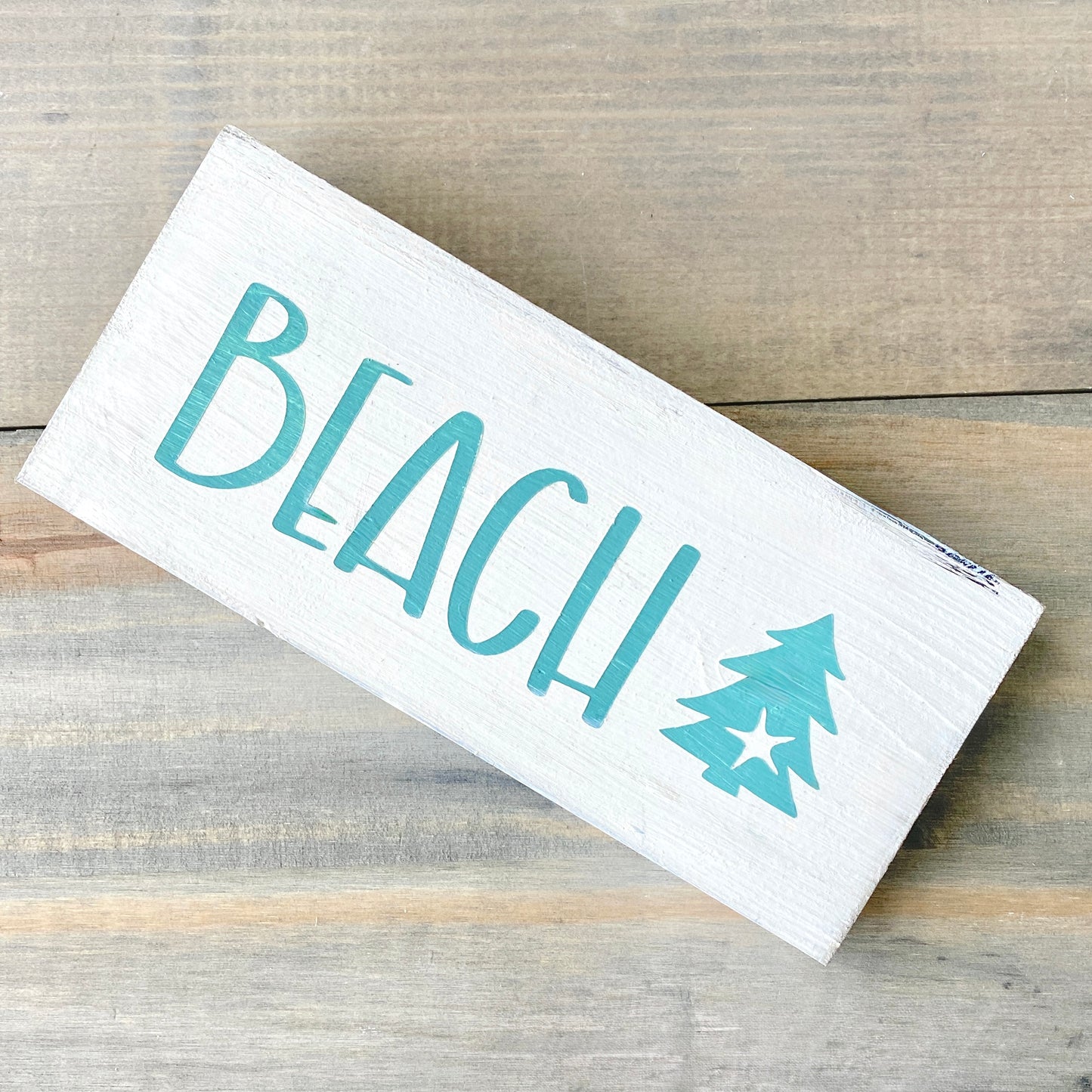 White sign with beach and christmas tree on a wood background