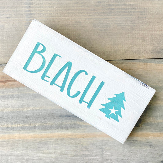 White sign with beach and christmas tree on a wood background