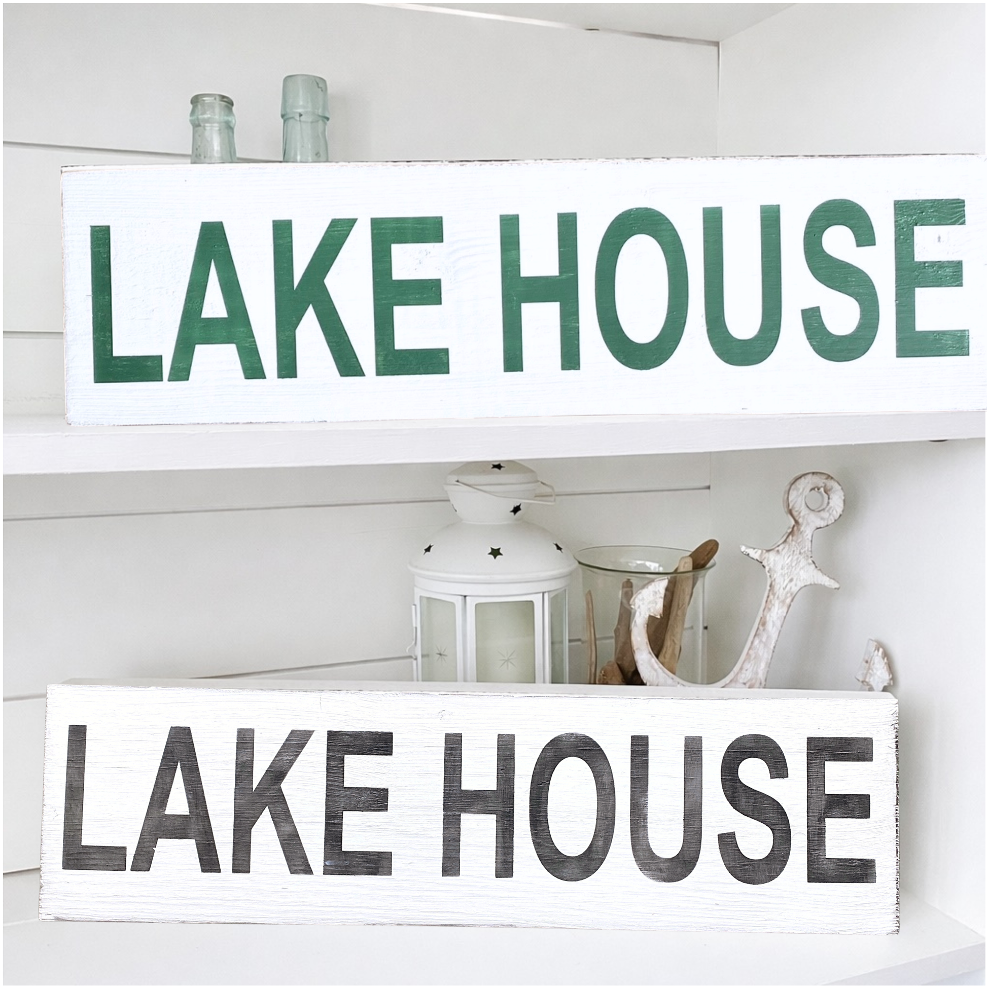 Two lake house signs on a shelf with other nautical decor