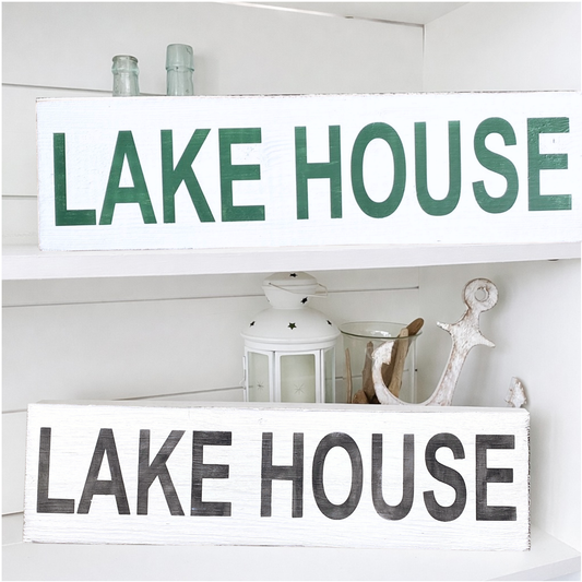 Two lake house signs on a shelf with other nautical decor