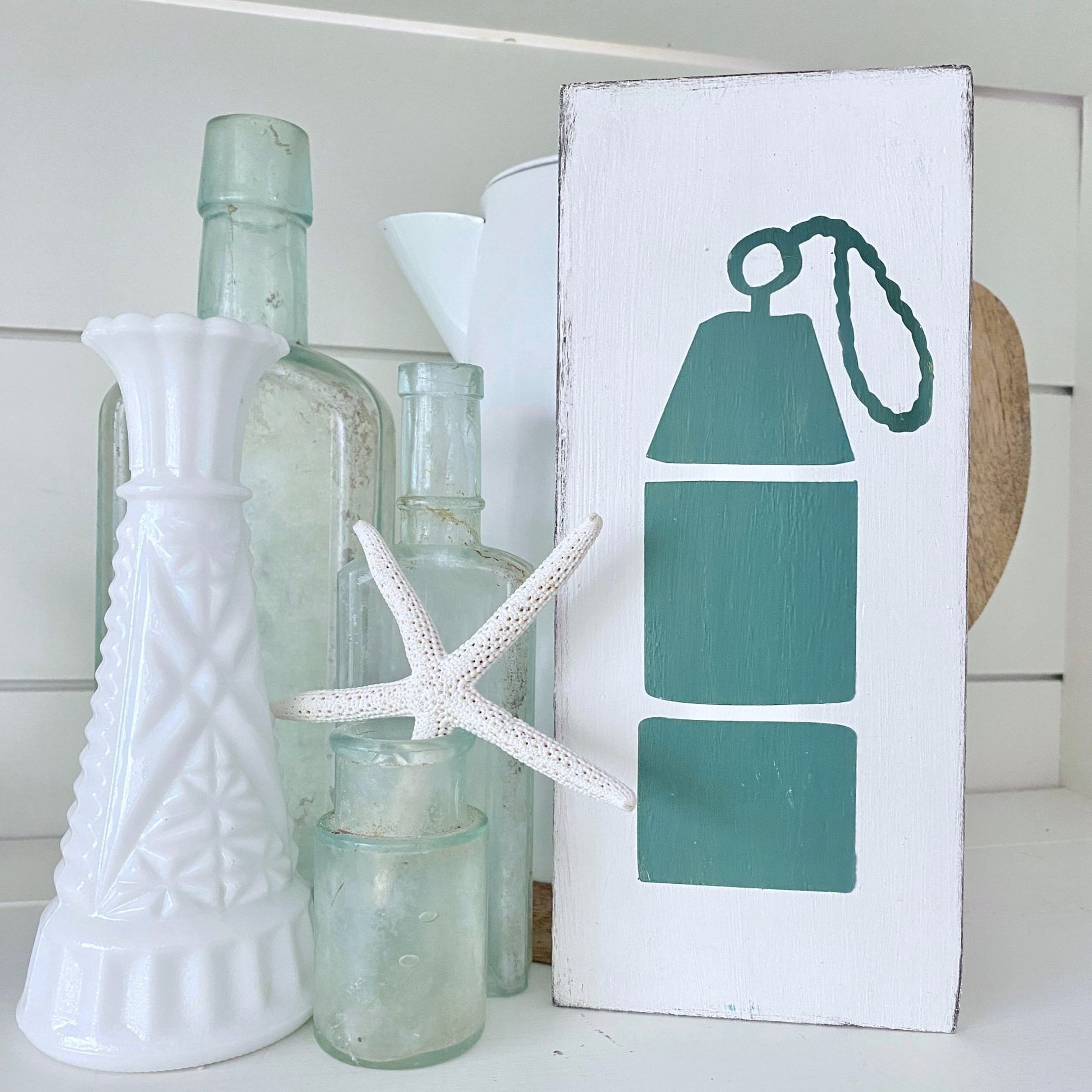 Decorative shelf with bottles, a starfish, and a sign with an oar design.
