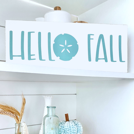 Decorative sign with 'Hello Fall' text on a shelf with decorative items.
