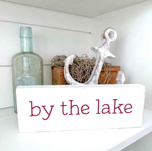 Decorative shelf with anchor, bottle, and 'by the lake' sign on a white background