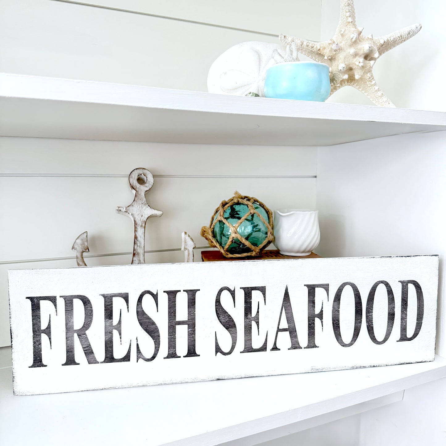 Decorative shelf with 'Fresh Seafood' sign and nautical-themed decor.