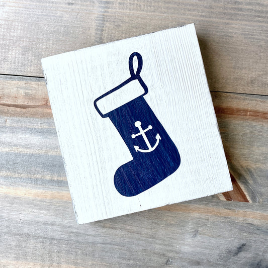 Wooden dign with a blue stocking design featuring an anchor on a wooden surface