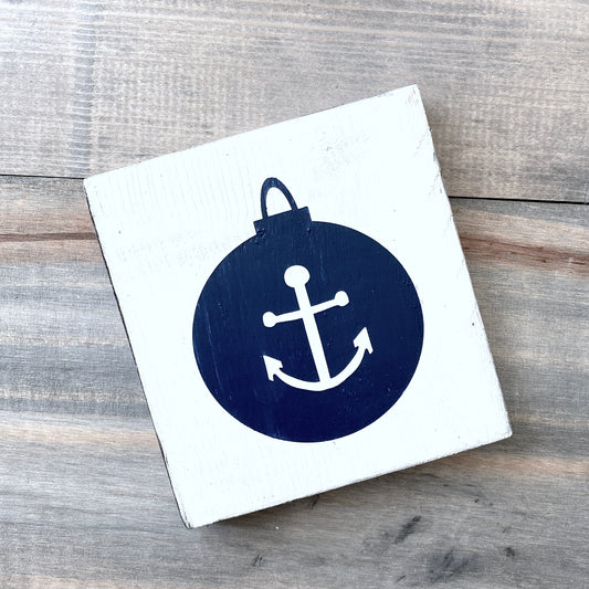 Square wooden block with a navy blue anchor design on a wooden surface
