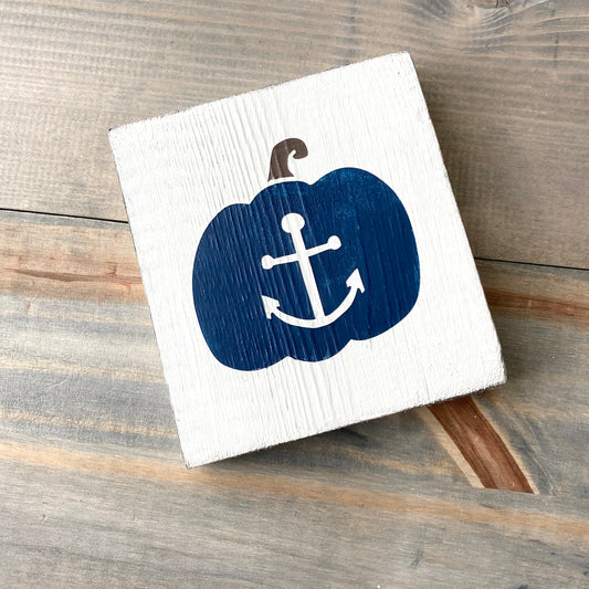 Decorative pumpkin with an anchor design on a wooden block