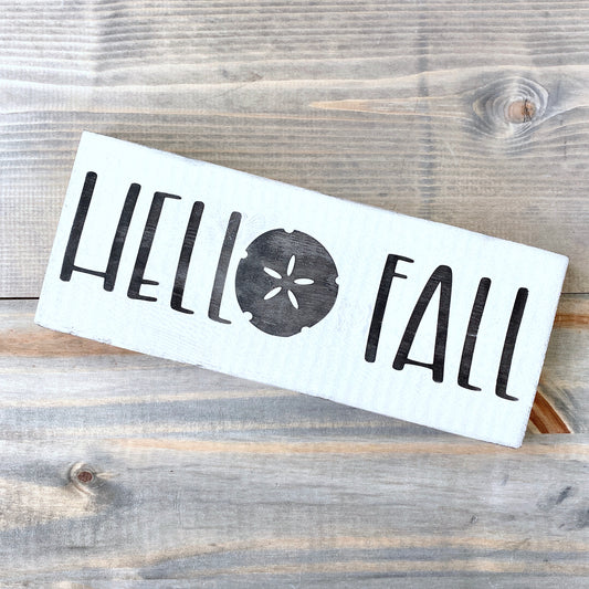 White sign with 'Hello Fall' text on a wooden surface