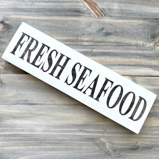 Wooden sign with 'FRESH SEAFOOD' text on a wooden surface