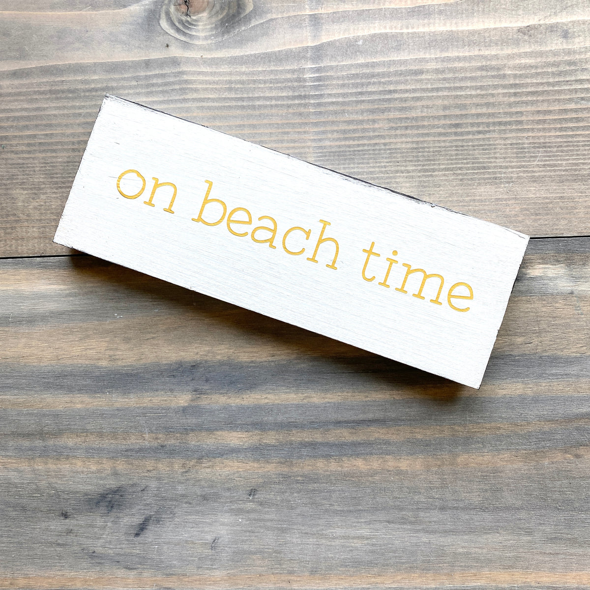 White sign with 'on beach time' text on a wooden surface