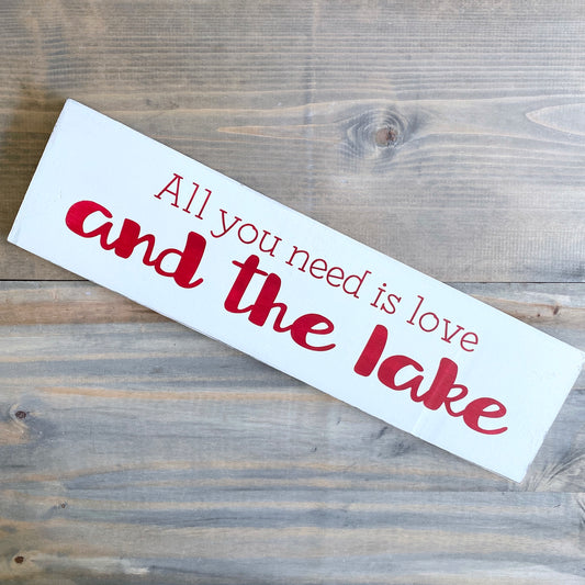 Wooden sign with 'All you need is love and the lake' text on a wooden surface