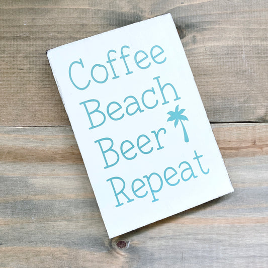 Sign with 'Coffee Beach Beer Repeat' text on a wooden surface