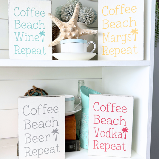 Decorative signs with humorous phrases on a shelf with decorative items. Coffee beach "drink" repeat signs coastal home decor signs