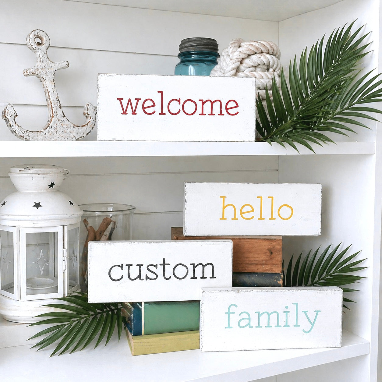Decorative shelf with 'welcome', 'hello', 'custom', and 'family' signs, lantern, and plants.