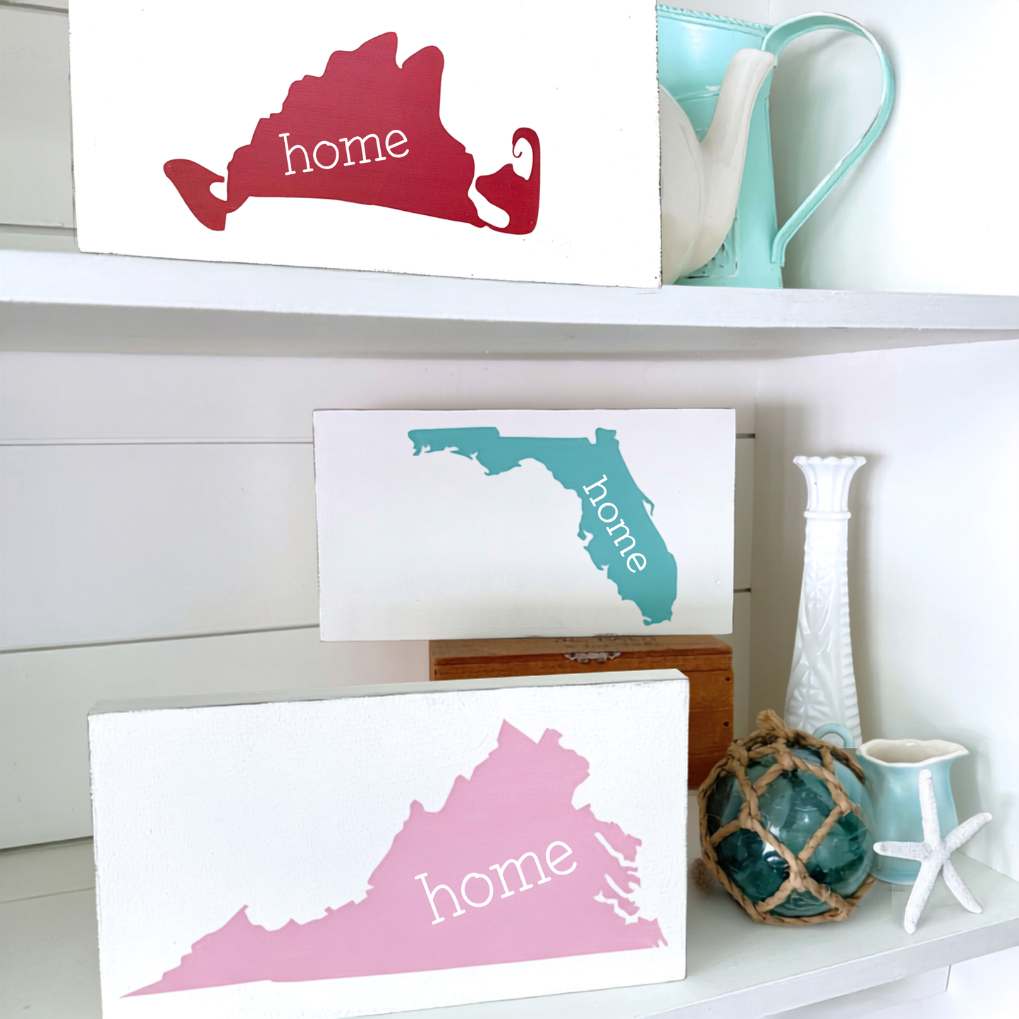 Decorative signs of states with 'home' text on a shelf with decorative items.