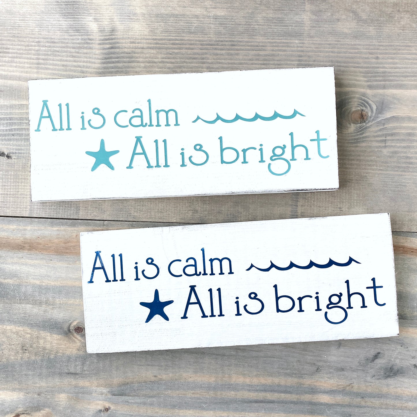 Two rectangular signs with text and a starfish on a wooden background All is calm, all is bright, coastal christmas sign