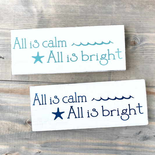 Two rectangular signs with text and a starfish on a wooden background All is calm, all is bright, coastal christmas sign